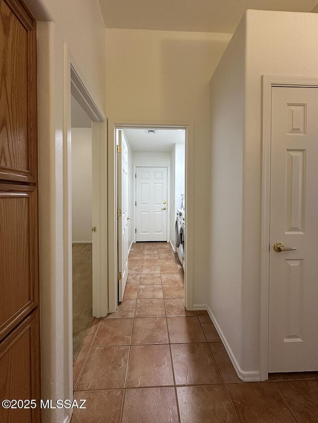 hall featuring light tile patterned flooring and washer / dryer