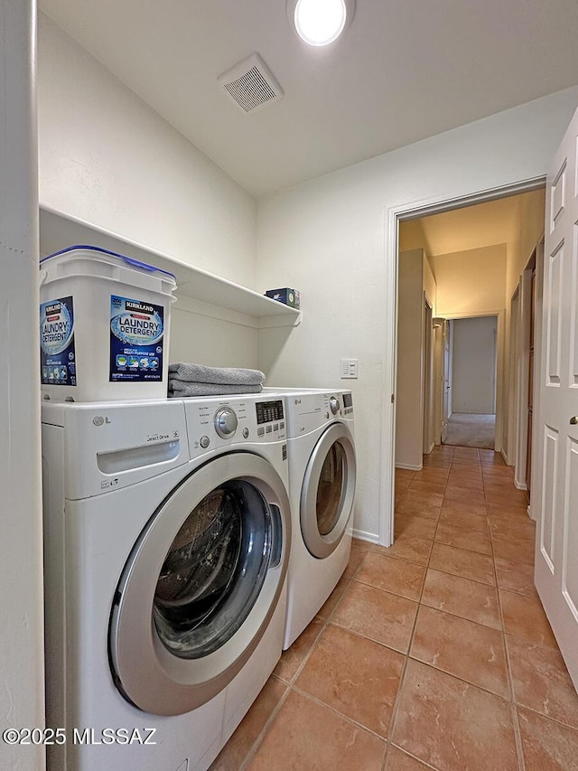 clothes washing area with light tile patterned floors and washer and clothes dryer