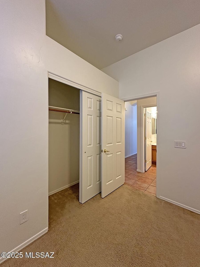 unfurnished bedroom with light carpet and a closet