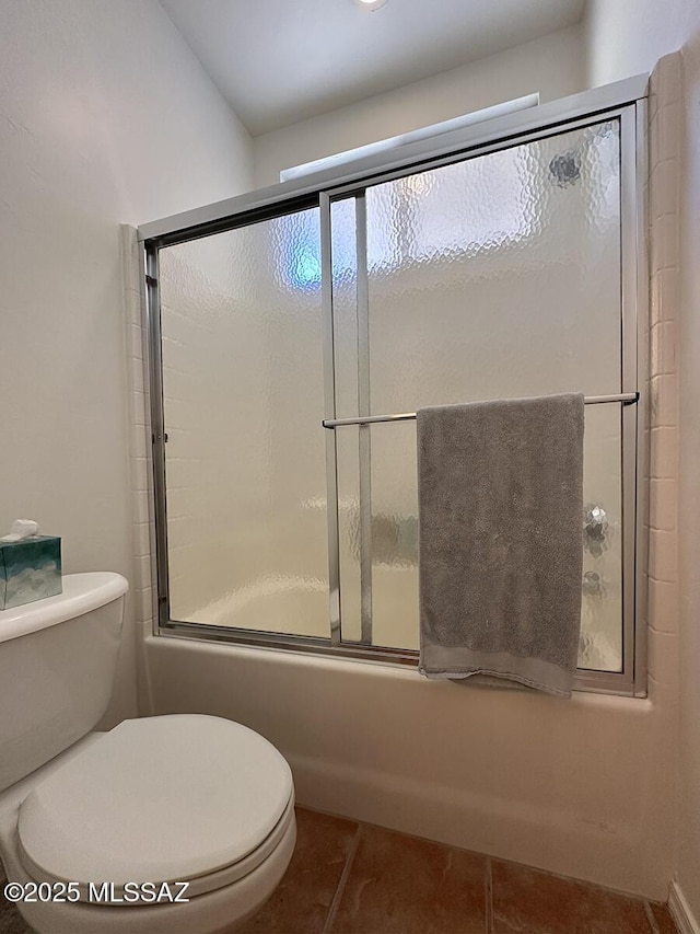 bathroom featuring tile patterned flooring, toilet, and combined bath / shower with glass door