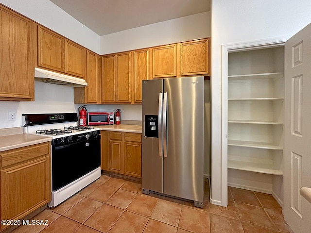 kitchen featuring stainless steel refrigerator with ice dispenser, light tile patterned floors, and range with gas stovetop