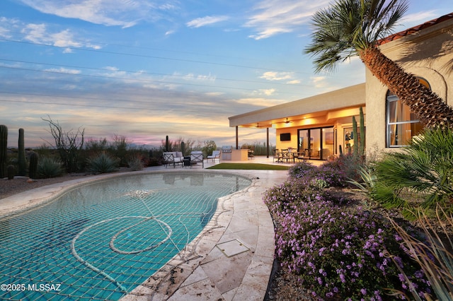 pool at dusk featuring a patio