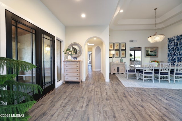 interior space featuring hardwood / wood-style floors, an inviting chandelier, and a tray ceiling