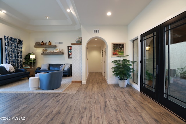 interior space with a tray ceiling, french doors, and hardwood / wood-style flooring