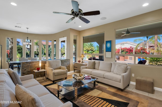 tiled living room featuring ceiling fan with notable chandelier