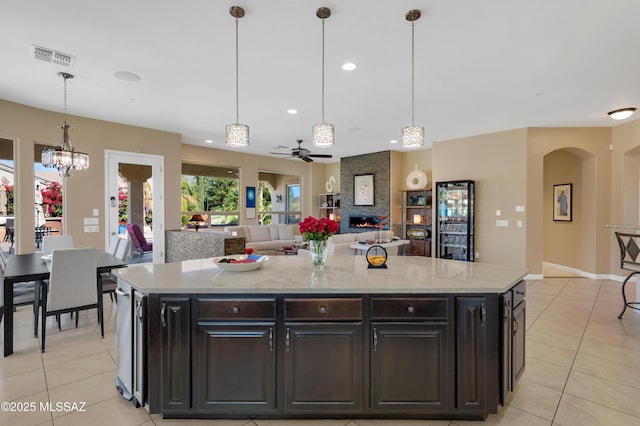 kitchen featuring light stone countertops, decorative light fixtures, a kitchen island, and ceiling fan