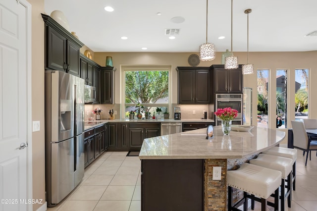 kitchen featuring a healthy amount of sunlight, backsplash, sink, a kitchen island, and stainless steel appliances