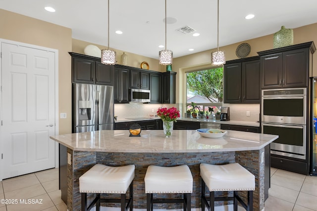 kitchen with a breakfast bar area, a center island, and appliances with stainless steel finishes