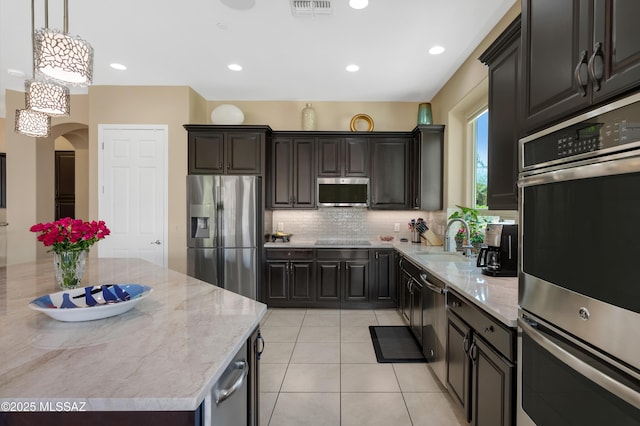 kitchen with sink, stainless steel appliances, pendant lighting, decorative backsplash, and a kitchen island