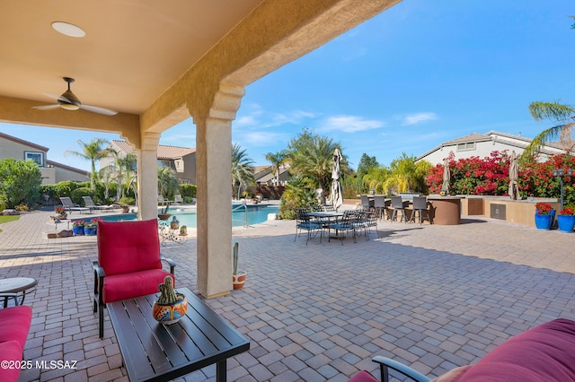 view of patio with an outdoor bar, ceiling fan, and a community pool