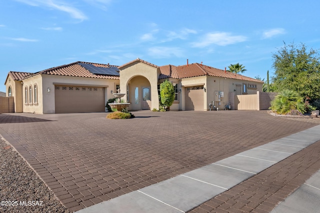 mediterranean / spanish house featuring solar panels and a garage