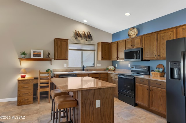 kitchen featuring a center island, black appliances, light stone counters, a breakfast bar, and sink