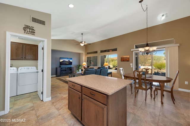 kitchen with ceiling fan with notable chandelier, washer and dryer, pendant lighting, lofted ceiling, and a kitchen island