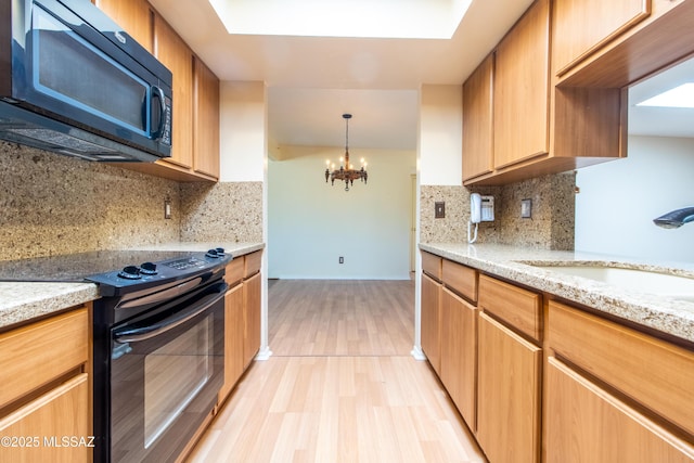 kitchen featuring an inviting chandelier, black appliances, sink, tasteful backsplash, and light hardwood / wood-style floors