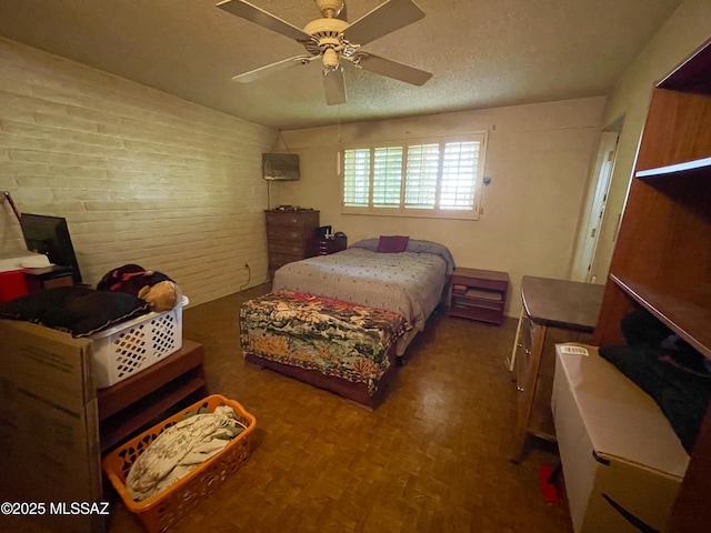 bedroom featuring ceiling fan, dark hardwood / wood-style flooring, brick wall, and a textured ceiling