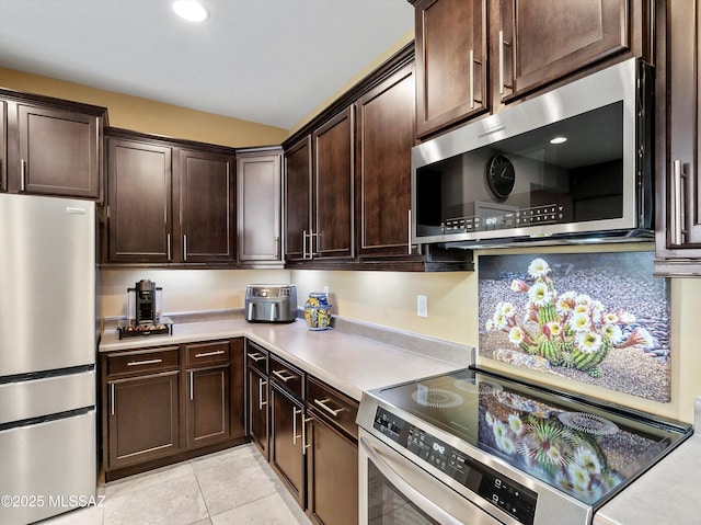 kitchen with appliances with stainless steel finishes, dark brown cabinetry, and light tile patterned floors