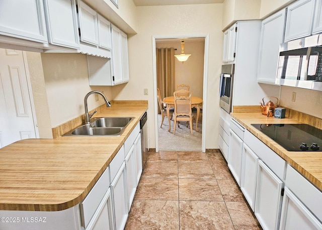 kitchen featuring sink, white cabinetry, stainless steel appliances, light carpet, and decorative light fixtures