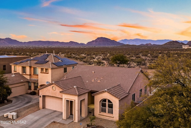 view of front of property with a tiled roof, concrete driveway, a mountain view, and stucco siding