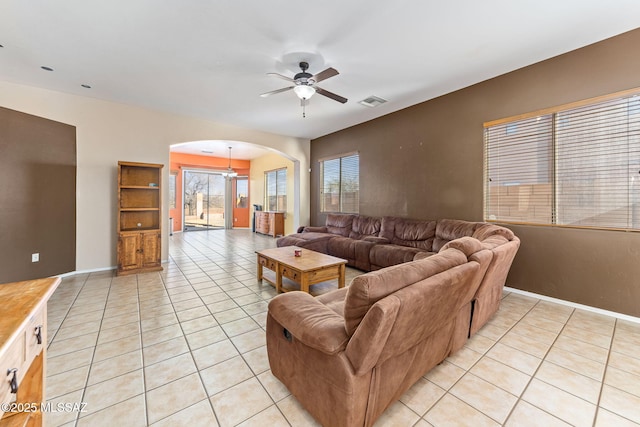 living room featuring light tile patterned floors, ceiling fan, visible vents, and arched walkways