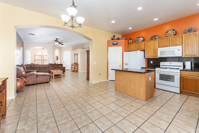 kitchen featuring arched walkways, white appliances, light tile patterned floors, and dark countertops