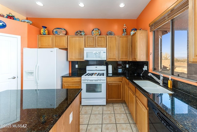 kitchen featuring light tile patterned floors, white appliances, a sink, backsplash, and dark stone counters