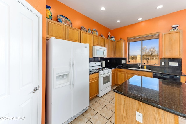 kitchen featuring recessed lighting, light tile patterned flooring, a sink, dark stone countertops, and white appliances