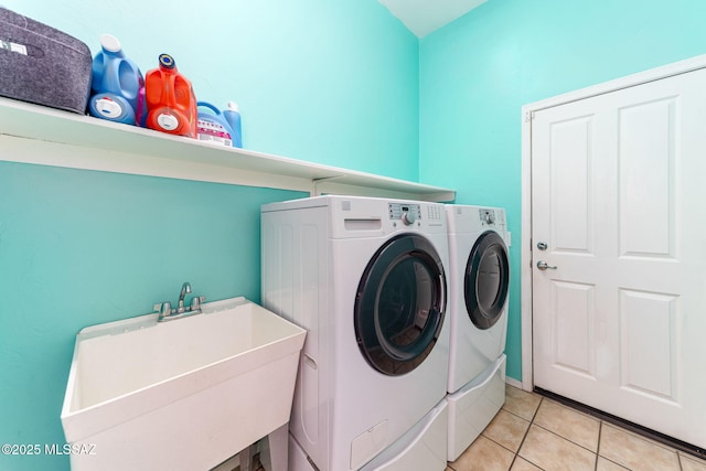 laundry room with laundry area, light tile patterned flooring, a sink, and washing machine and clothes dryer