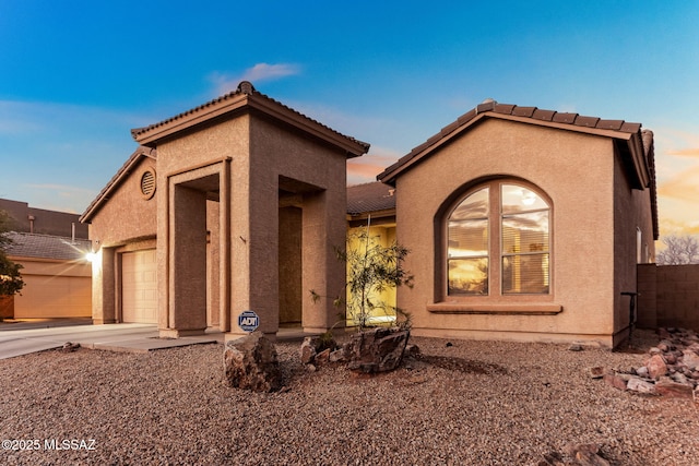 view of front of home with a garage, driveway, and stucco siding