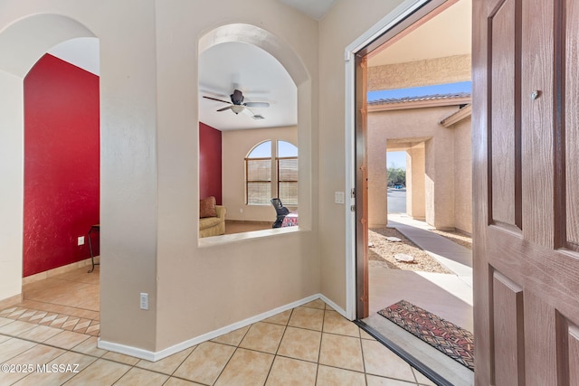 hall with a healthy amount of sunlight, baseboards, and tile patterned floors