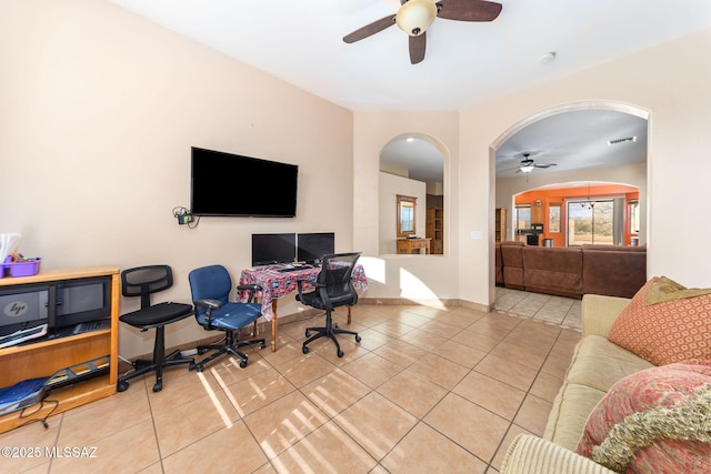 tiled home office featuring arched walkways, ceiling fan, visible vents, and baseboards