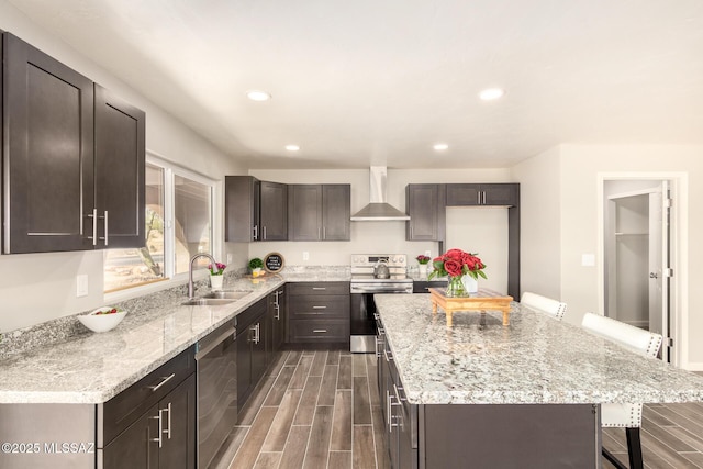 kitchen featuring a kitchen island, sink, a kitchen bar, stainless steel appliances, and wall chimney exhaust hood