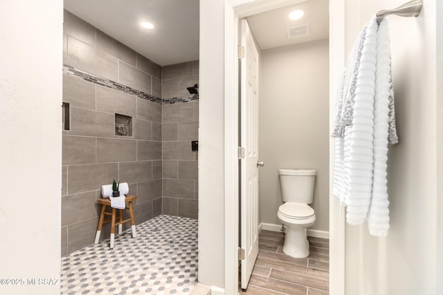 bathroom with toilet and a tile shower