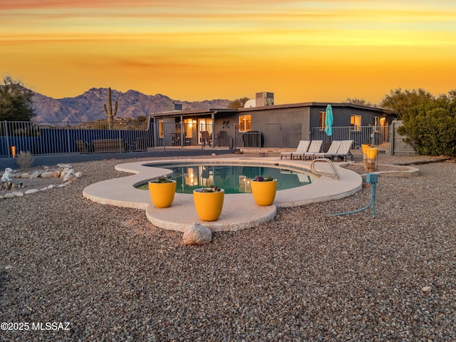 pool at dusk featuring a mountain view and a patio area