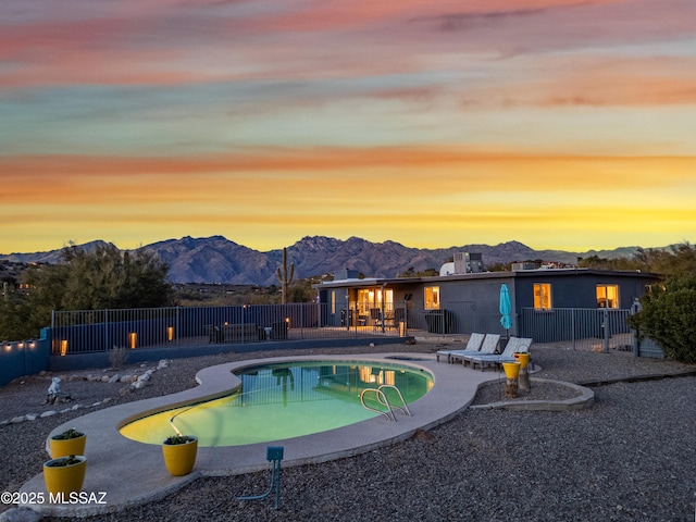 pool at dusk with a mountain view and a patio area