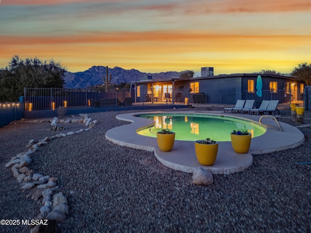 pool at dusk featuring a mountain view and a patio area