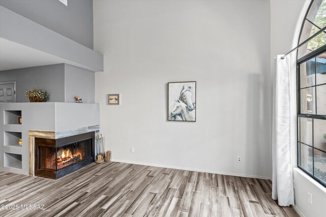 5304 N Paseo De La Terraza, Tucson, AZ 85750 - unfurnished living room with wood finished floors, a multi sided fireplace, a high ceiling, and baseboards