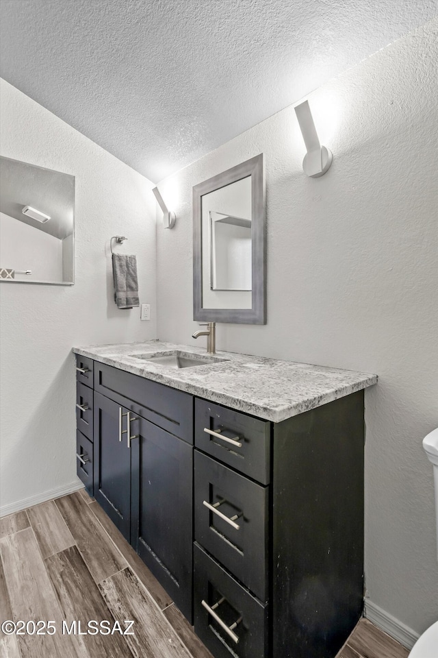 bathroom with a textured ceiling, toilet, and vanity