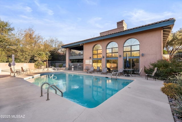 community pool with fence and a patio