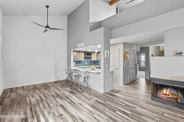 kitchen with tasteful backsplash, a breakfast bar area, stainless steel microwave, and wood finished floors