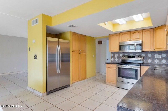 kitchen featuring a raised ceiling, light tile patterned floors, backsplash, and appliances with stainless steel finishes