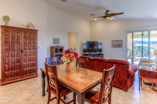 dining space with ceiling fan, light tile patterned floors, and vaulted ceiling