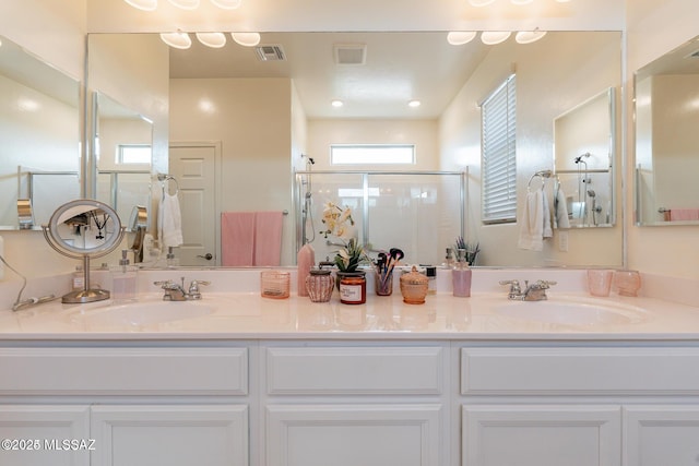 bathroom with a shower with shower door and vanity