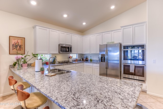 kitchen featuring white cabinetry, stainless steel appliances, sink, kitchen peninsula, and a breakfast bar