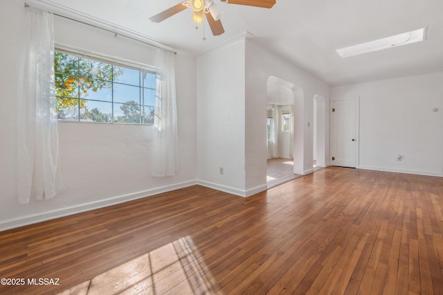 unfurnished room featuring hardwood / wood-style floors, a skylight, and ceiling fan