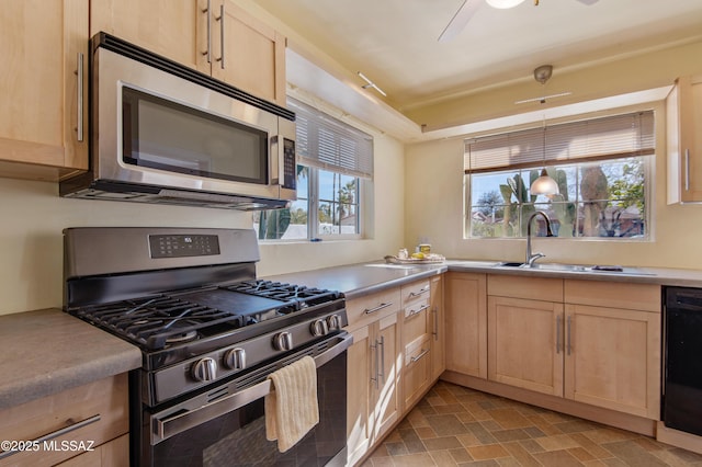 kitchen featuring light brown cabinetry, sink, hanging light fixtures, and appliances with stainless steel finishes