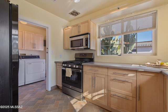 kitchen featuring stainless steel appliances, light brown cabinetry, and washing machine and dryer