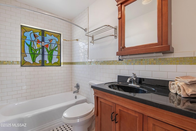 full bathroom with vanity, tiled shower / bath, tile walls, and toilet