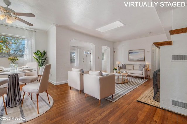 living room with hardwood / wood-style flooring, a skylight, and ceiling fan