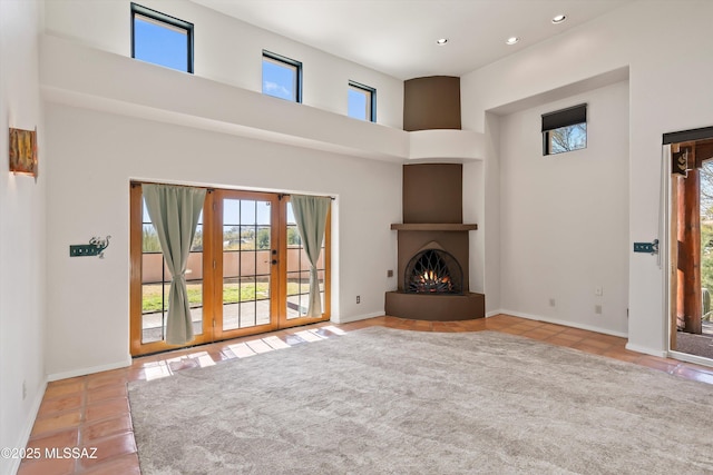 unfurnished living room featuring light tile patterned floors, a large fireplace, and a towering ceiling