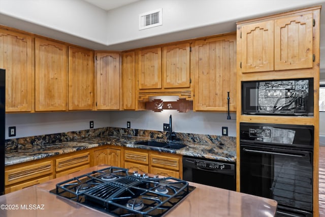 kitchen with black appliances, dark stone counters, and sink